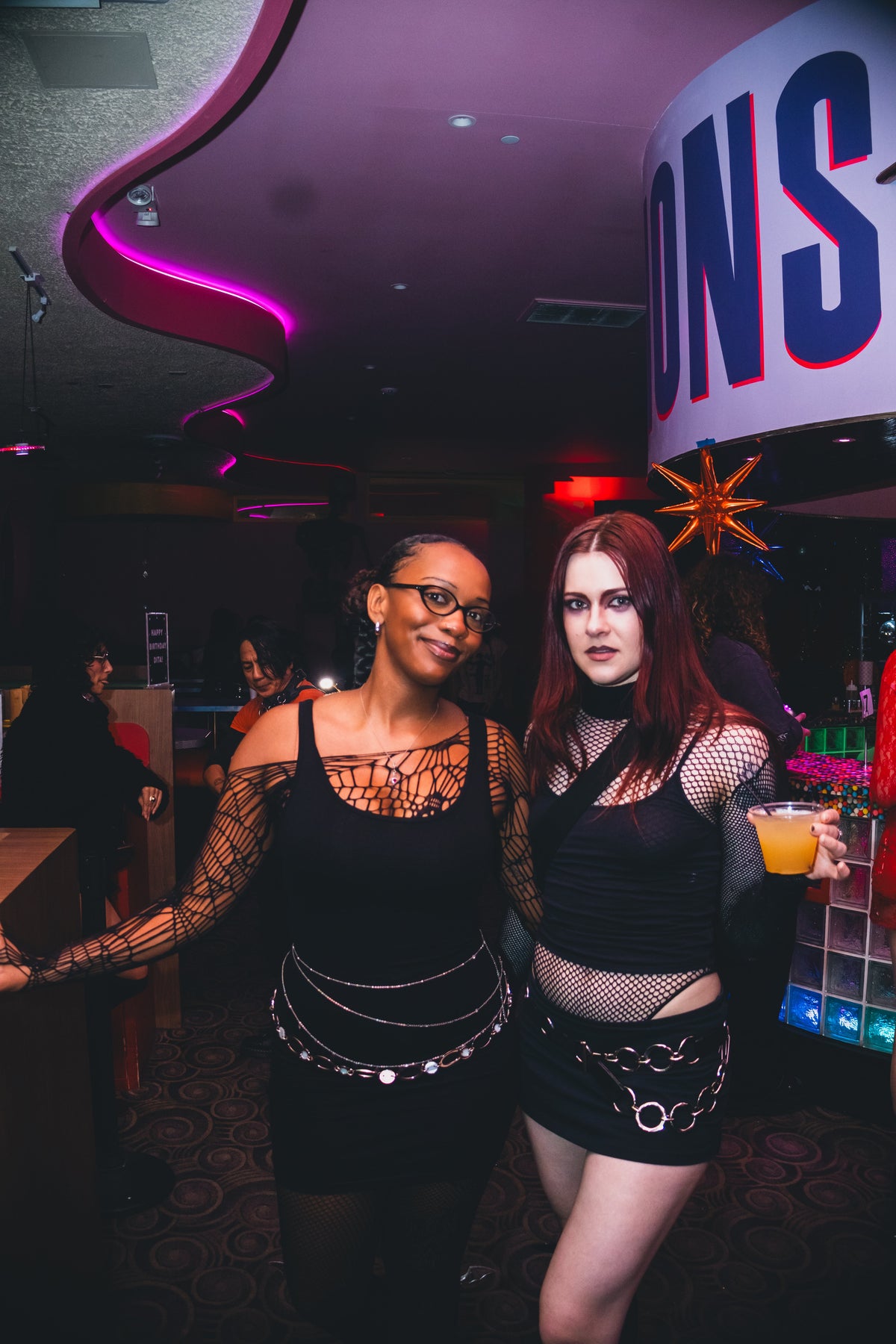 Two guests in black mesh outfits and silver chains at Xanadu