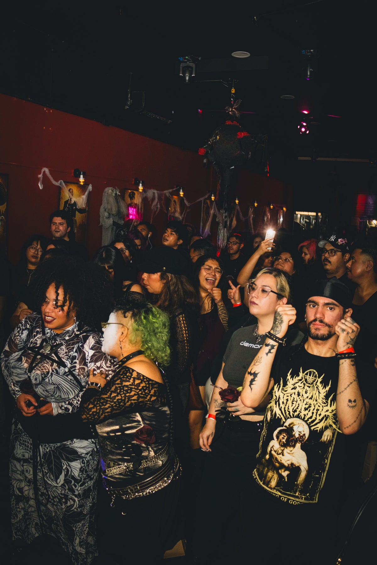 People on the Goth Cumbia dance floor in black outfits under dim lights.