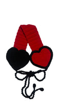 Red and black heart-shaped knitted item on a light gray background