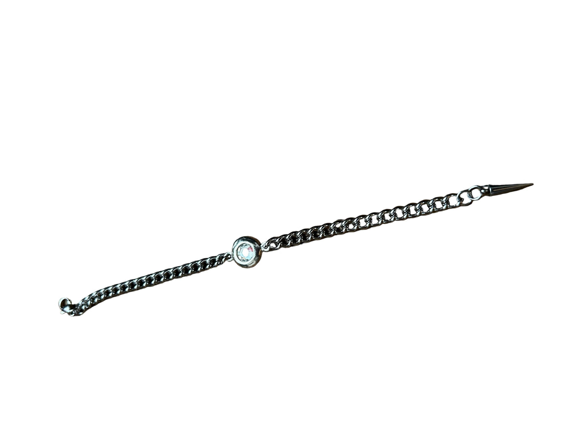 A silver-toned chain bracelet with a central round bezel-set stone, displayed diagonally on a dark brown wooden surface.