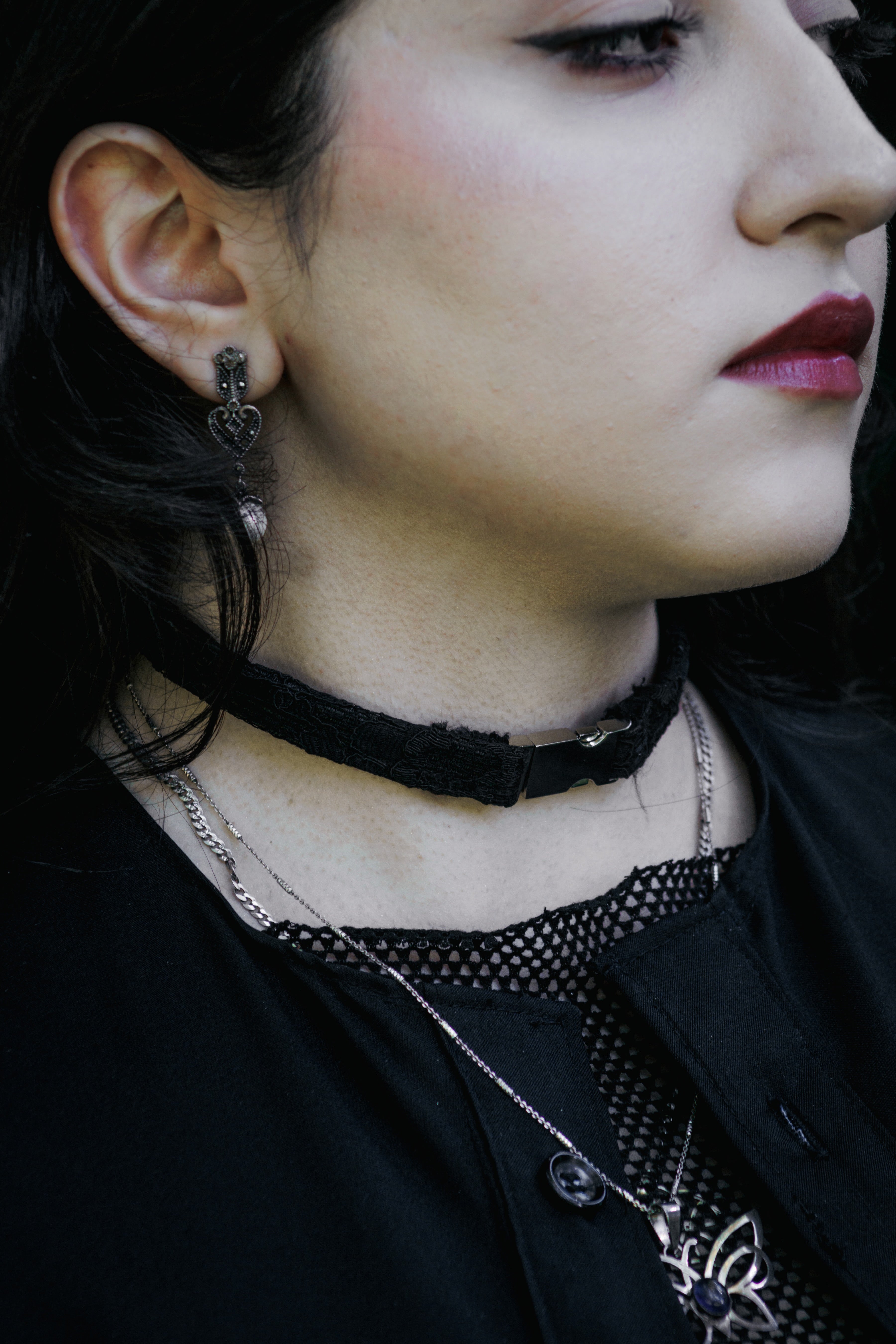 Close-up of a person wearing a black choker and dark clothing with a blurred background