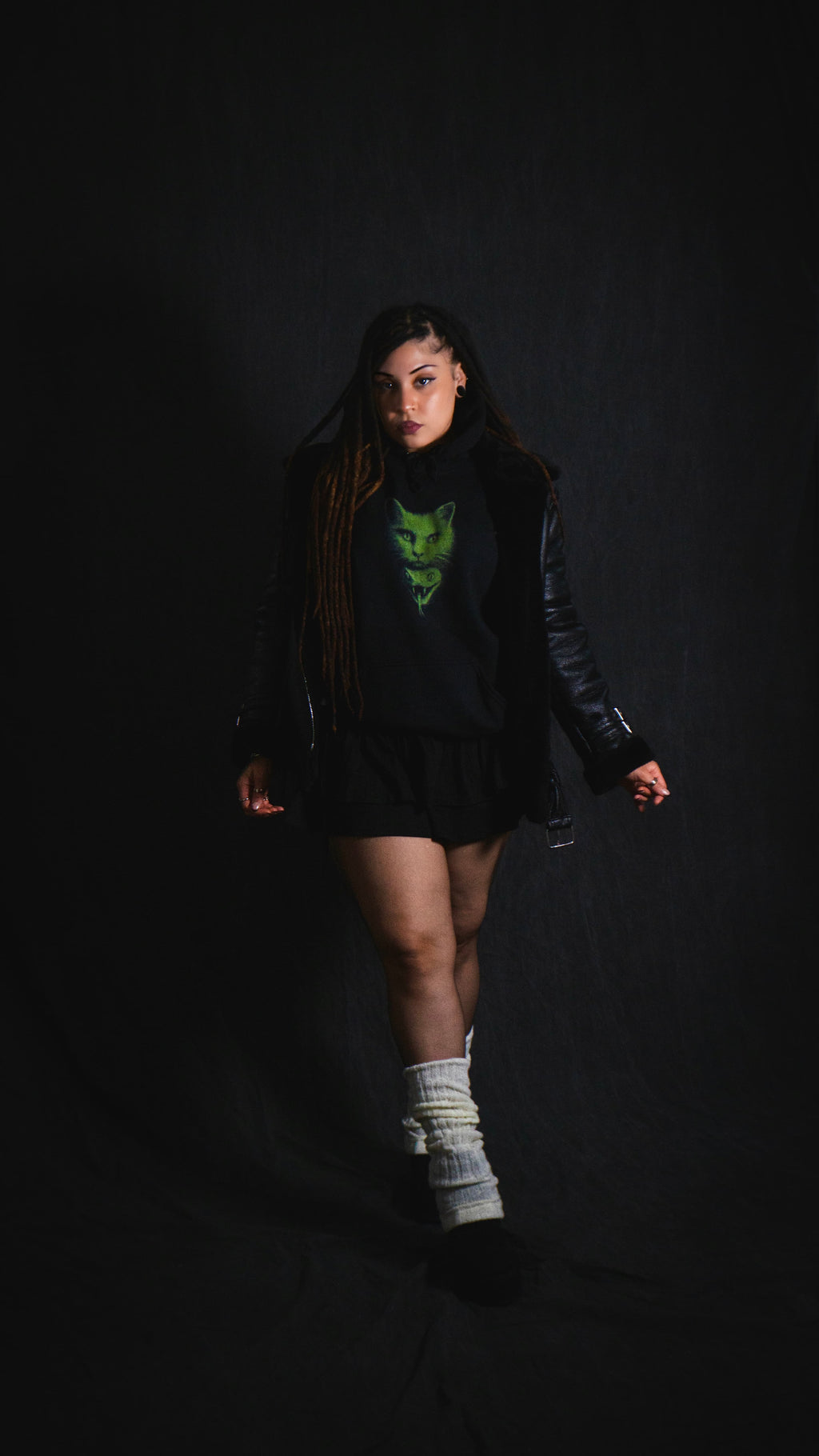 Person wearing a black outfit with a green logo on a dark background
