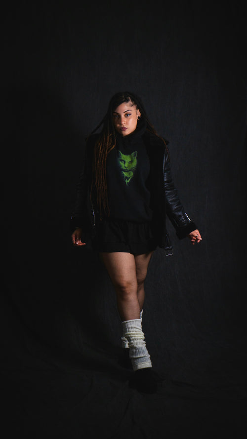 Person wearing a black outfit with a green logo on a dark background