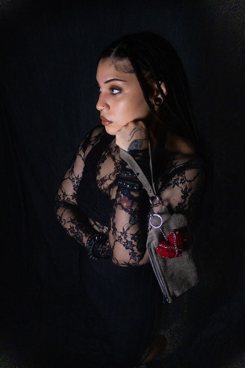 Person wearing a black lace garment with tattoos on a dark background