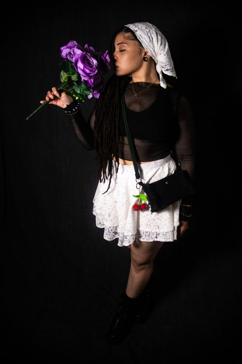 Person holding purple flowers against a black background
