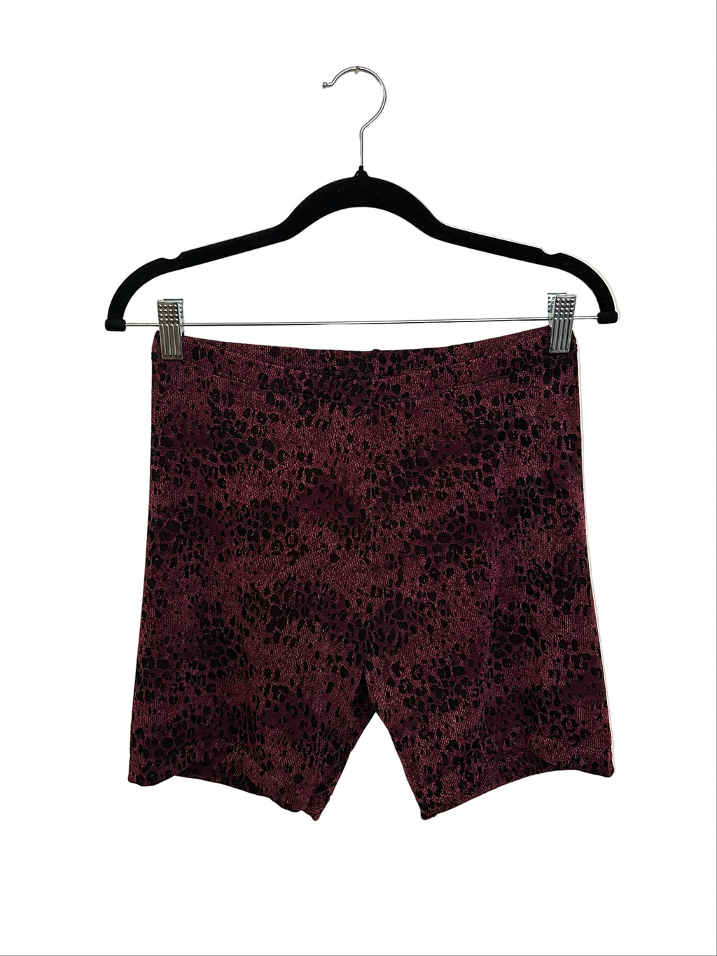 A pair of women's shorts in a dark purple and black leopard print pattern, clipped to a black hanger against a plain off-white background.
