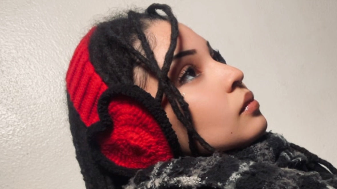 Person wearing a black and red knitted headband against a plain background