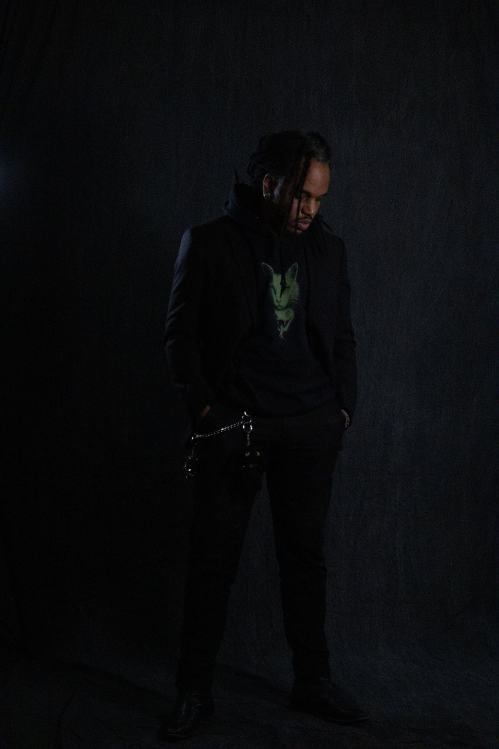 Person wearing a dark coat and pants against a black background