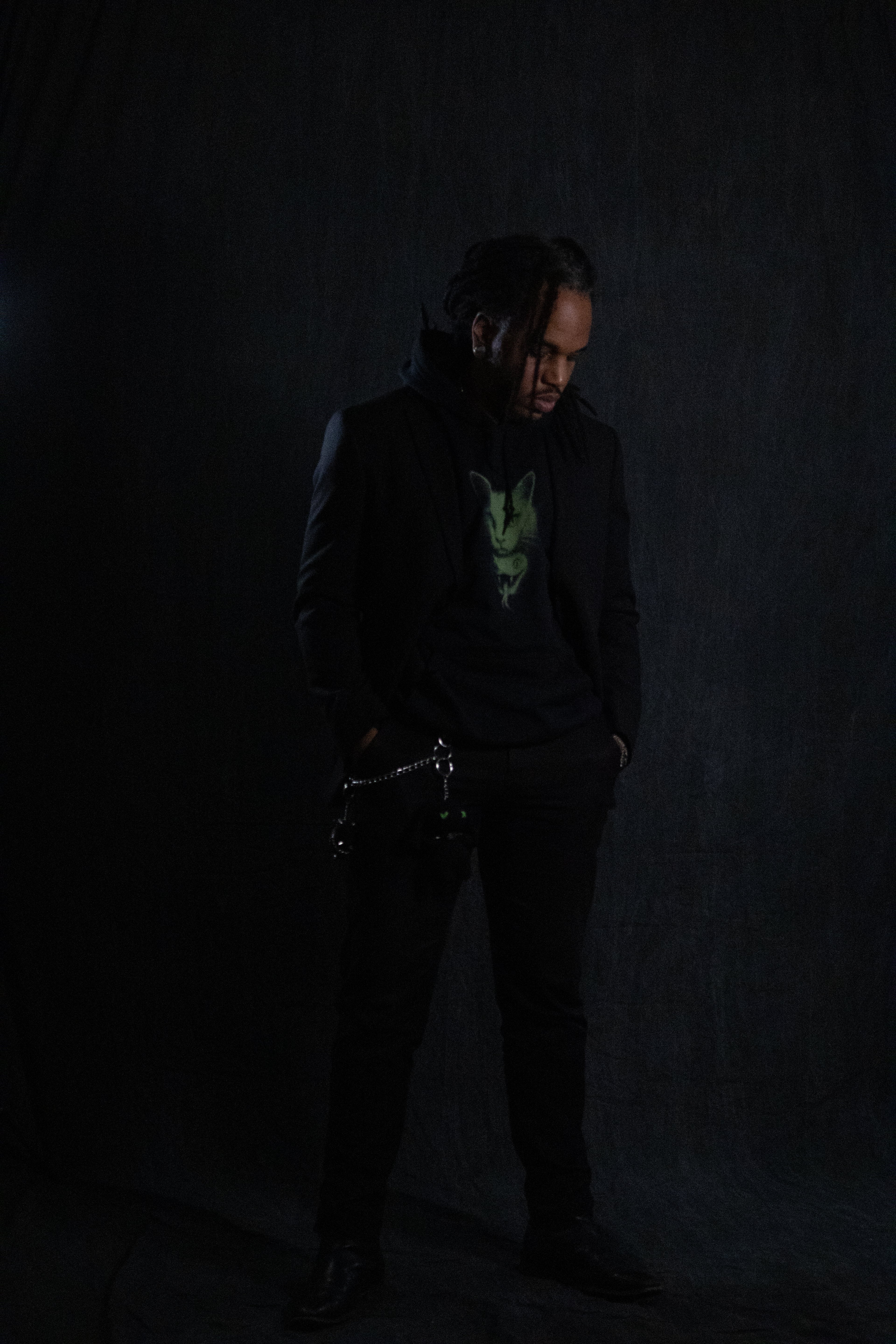 Person wearing a dark coat and pants against a black background